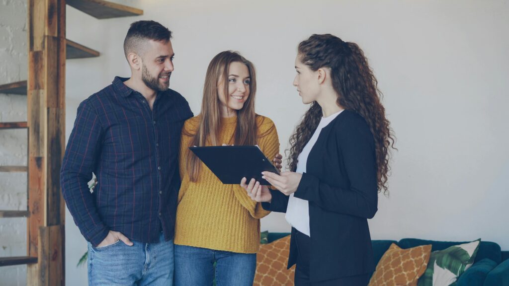 Couple discussing property options with a real estate agent indoors.